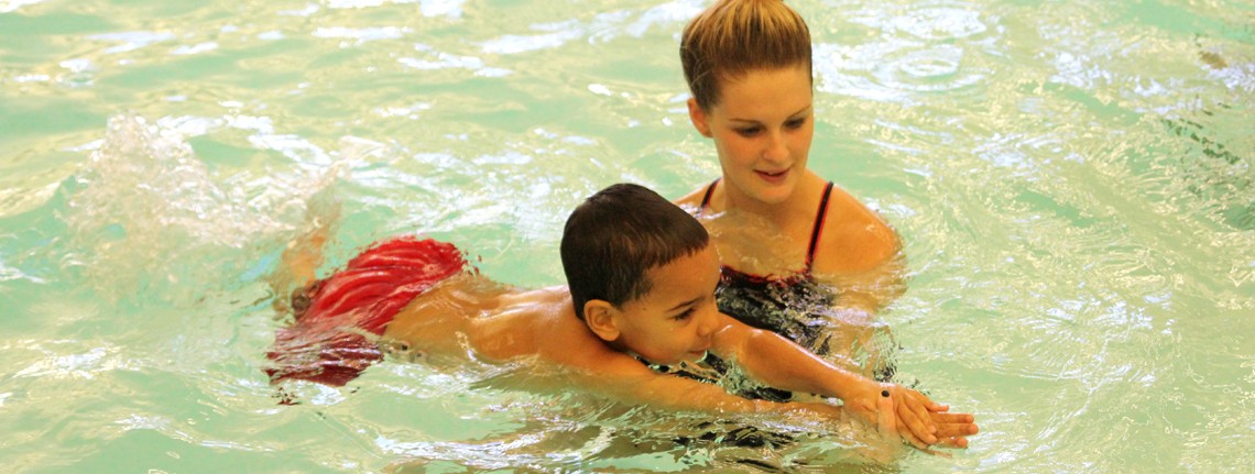 female aquatics instructor teaching a young boy to swim