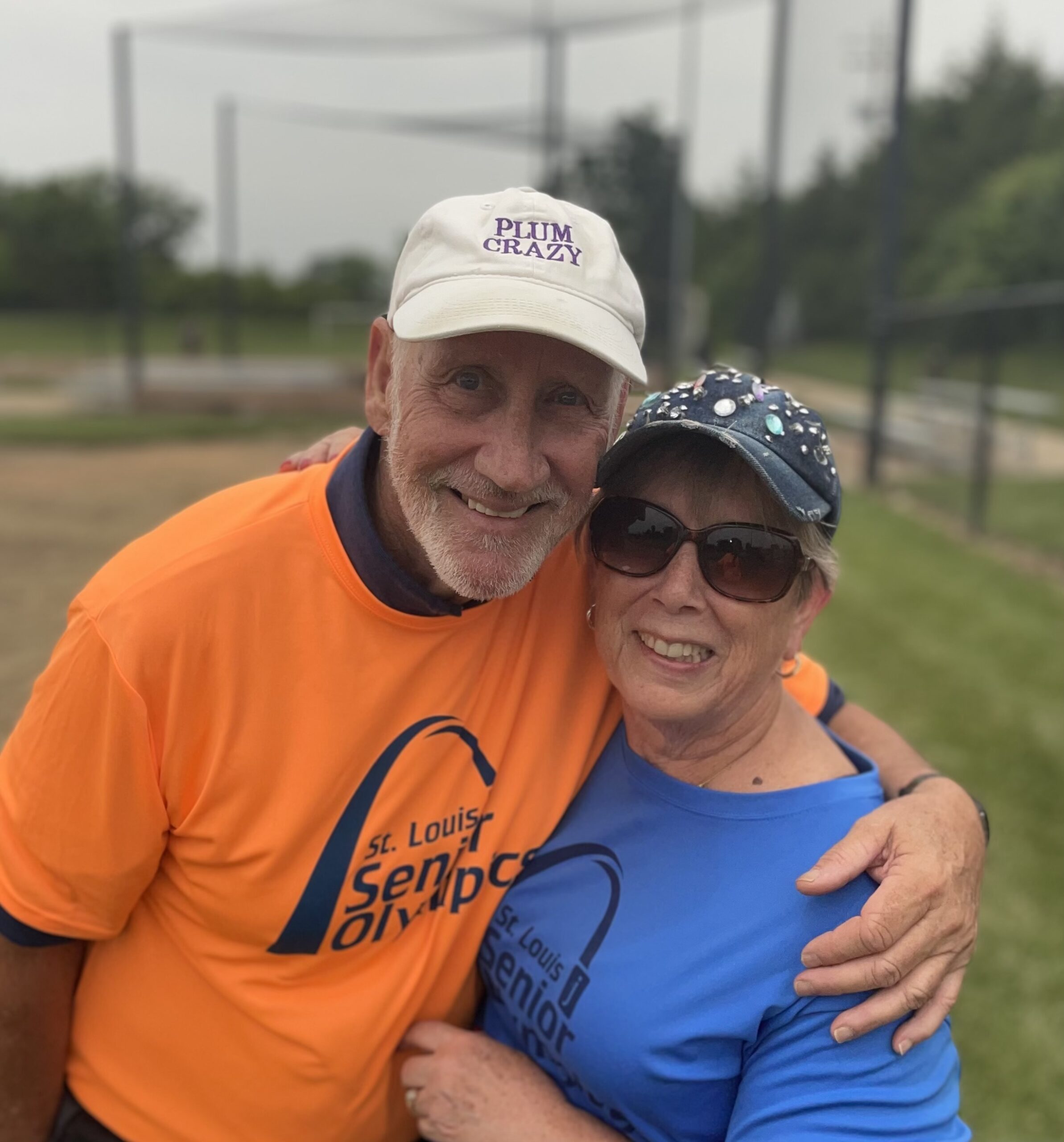 Two volunteers, man and a woman, where orange and blue St. Louis Senior Olympics T-shirts.
