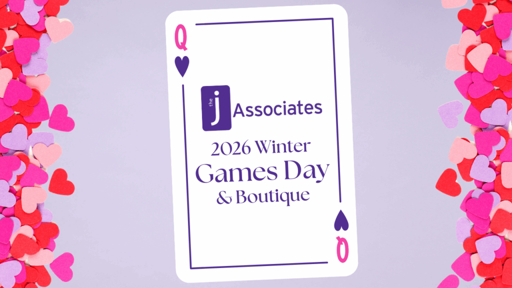 A Pink and Purple queen of hearts card sitz on a pastel purple background. Multi-shade pink heart-shaped confetti borders the edge. On the playing card is the J Associates logo and the words "Winter Games Day & Boutique.