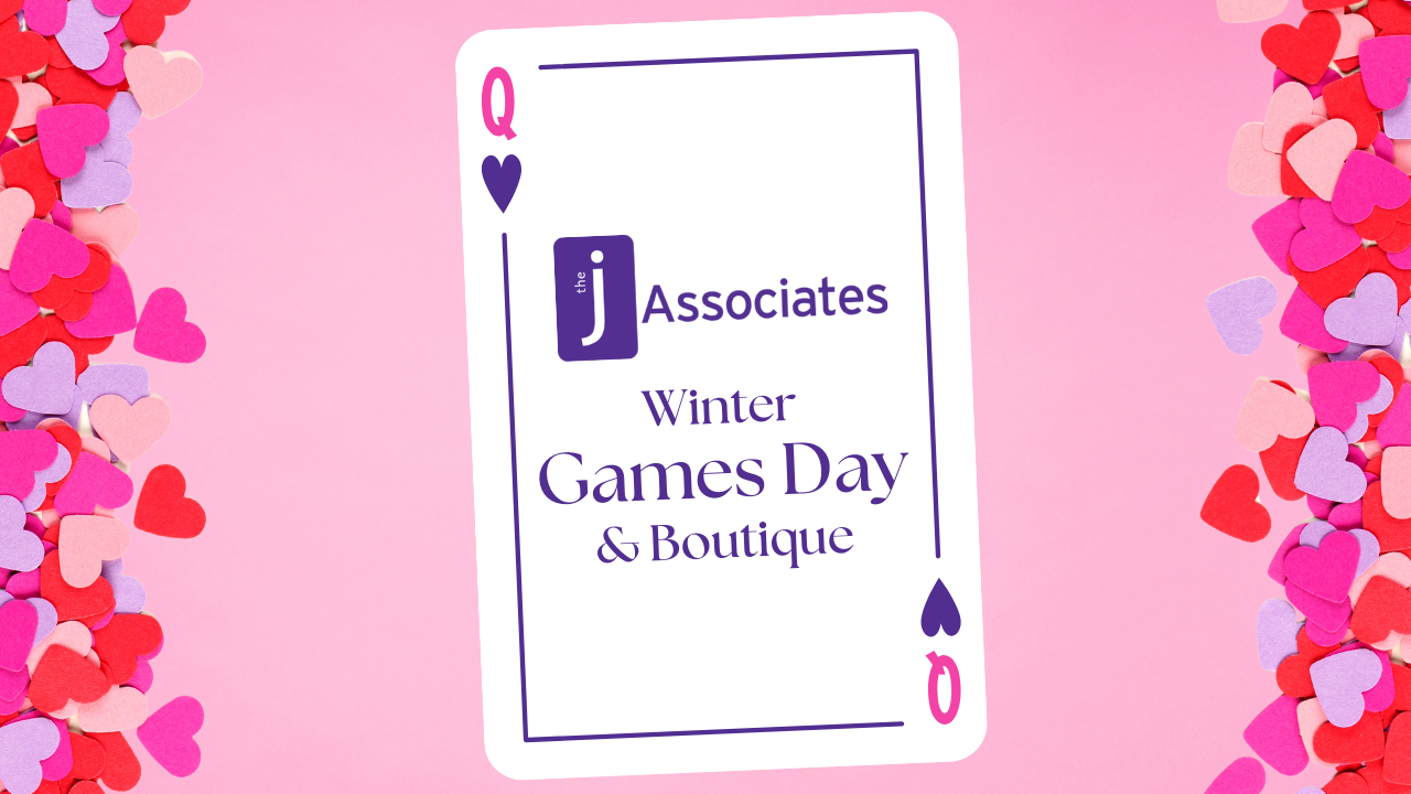 A Pink and Purple queen of hearts card sitz on a pink background. Multi-shade pink heart-shaped confetti borders the edge. On the playing card is the J Associates logo and the words "Winter Games Day & Boutique.