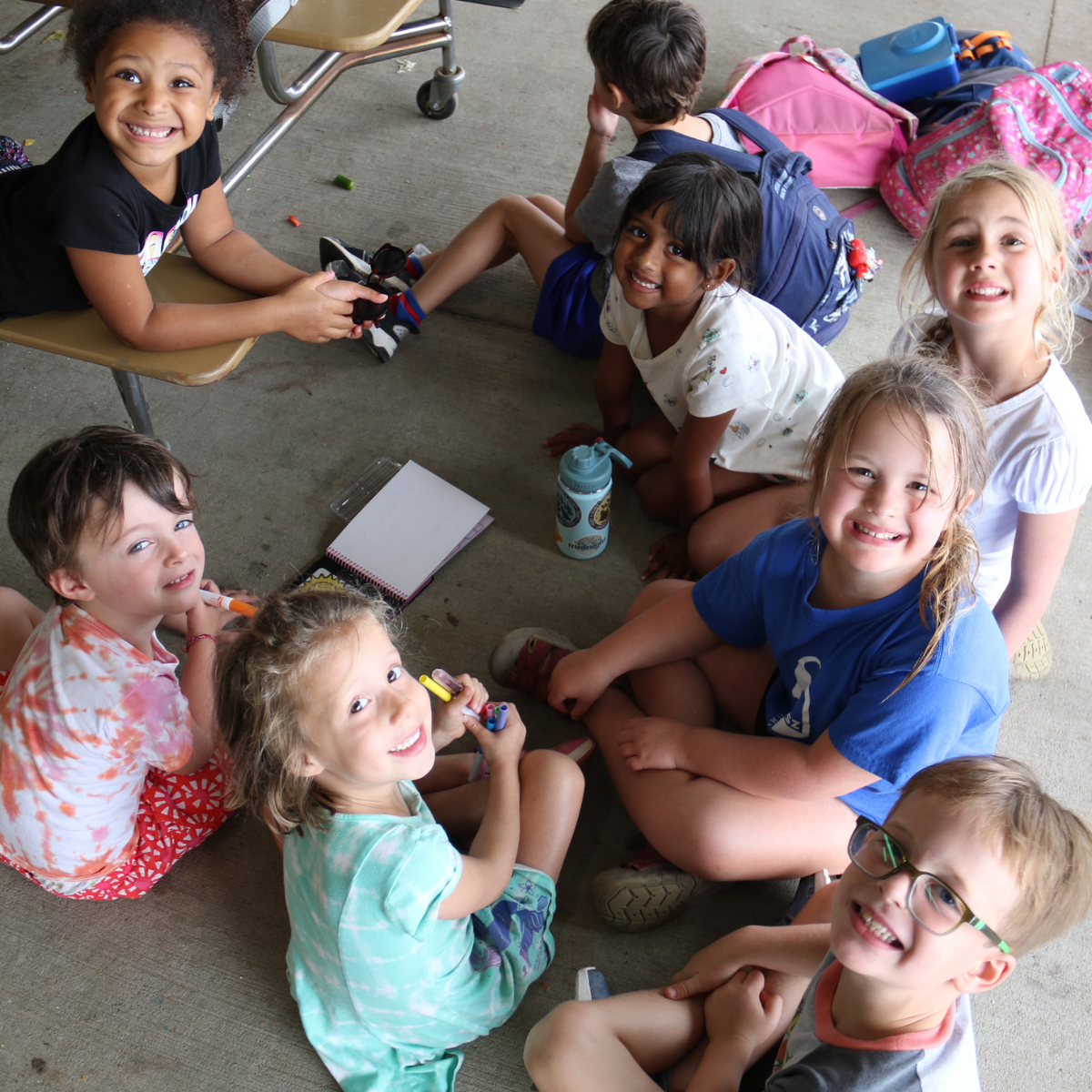 Photo from J Day Camps 2025 at The J - St. Louis: A group of eight boys and girls sit in a group, chatting with each other during free time.