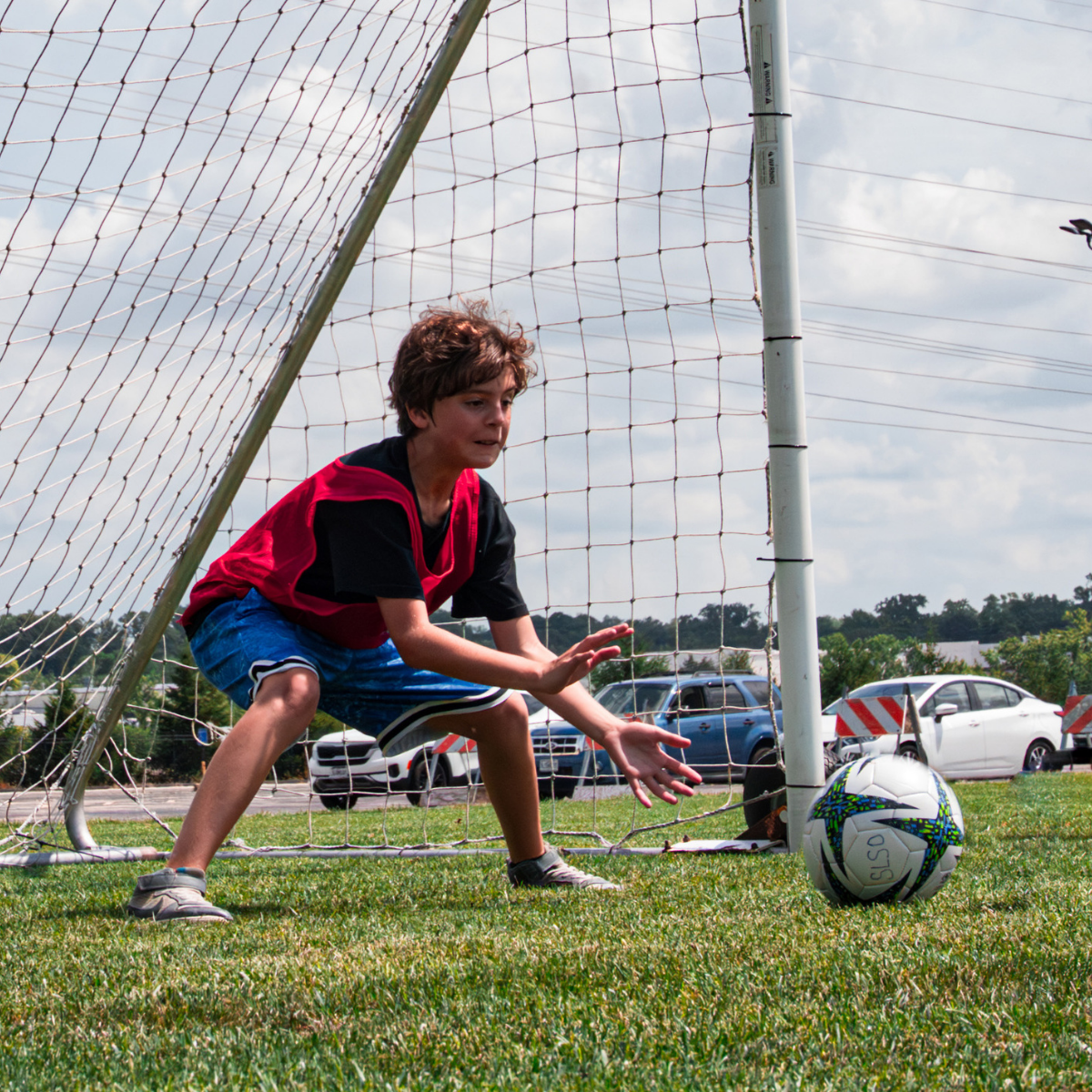Photo from J Day Camps 2025 at The J - St. Louis: A camper, a boy of perhaps 12, blocks a soccer ball from a goal on an outdoor soccer field.
